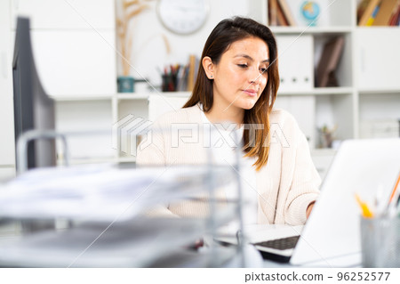 Woman sitting at workplace with computer in office Woman sitting at workplace with computer in office 96252577