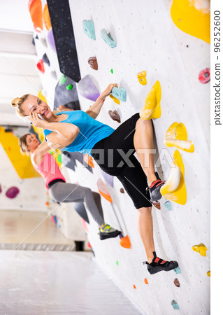 Woman talking on phone while exercising in climbing gym 96252600