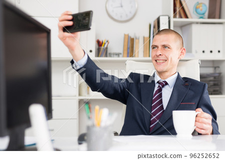 Male business consultant working in an office takes a selfie 96252652