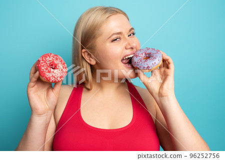 Fat girl eats sweet instead of do gym. Cyan background Fat girl eats sweet instead of do gym. Cyan background 96252756