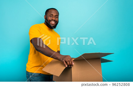 Happy boy receives a package from online shop order. Blue background. Happy boy receives a package from online shop order. Blue background. 96252808