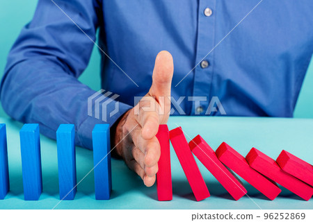 Businessman stops a chain fall like domino game. Concept of preventing crisis and failure in business. 96252869
