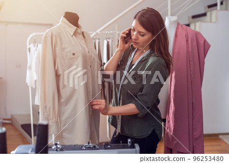 Seamstress works to new clothes ordered by internet client 96253480