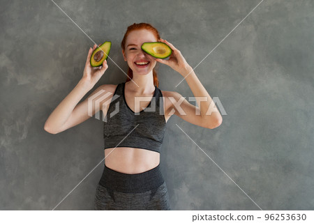 Athletic girl with gym clothes eats avocado at home 96253630