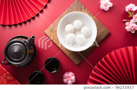 Tang Yuan(sweet dumplings balls), a traditional cuisine for Mid-autumn, Dongzhi (winter solstice ) and Chinese new year with plum flower and tea on red background. Tang Yuan(sweet dumplings balls), a traditional cuisine for Mid-autumn, Dongzhi (winter solstice ) and Chinese new year with plum flower and tea on red background. 96253937