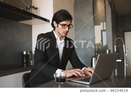 Businessman works from remote at house with a laptop due to coronavirus quarantine. Businessman works from remote at house with a laptop due to coronavirus quarantine. 96254019