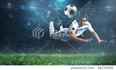 Soccer striker hits the ball with an acrobatic headshot in the air at the stadium Soccer striker hits the ball with an acrobatic headshot in the air at the stadium 96254090