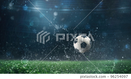 Close up of a soccer ball rolling on the playing field on a rainy night Close up of a soccer ball rolling on the playing field on a rainy night 96254097