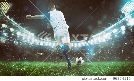 Close up of a soccer scene at night match with player in a white and blue uniform kicking the ball with power Close up of a soccer scene at night match with player in a white and blue uniform kicking the ball with power 96254115