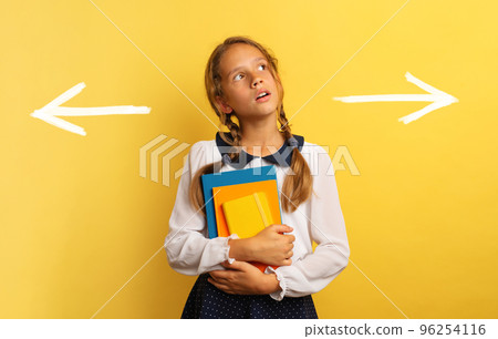 Young student is confused about the right arrow to select. Yellow background 96254116