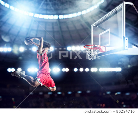 Jumping Player throws the ball in the basket in the stadium full of spectators 96254716