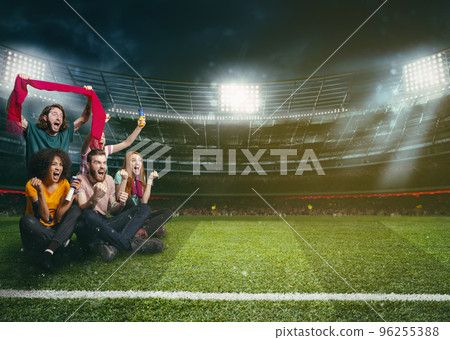 Soccer fans in the middle of the action during a night game at the stadium 96255388