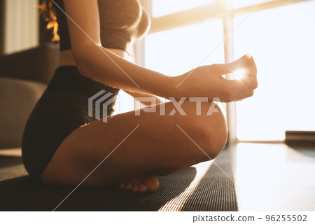 Young girl relaxing in yoga position in front of a bright window Young girl relaxing in yoga position in front of a bright window 96255502