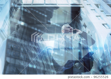 Senior businessman speaks on the mobile while walking in a modern city. Double exposure effect 96255526