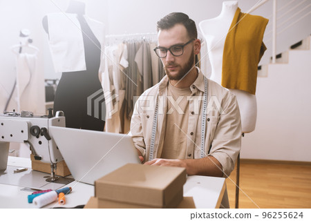 Seamstress works to new clothes ordered by internet client 96255624