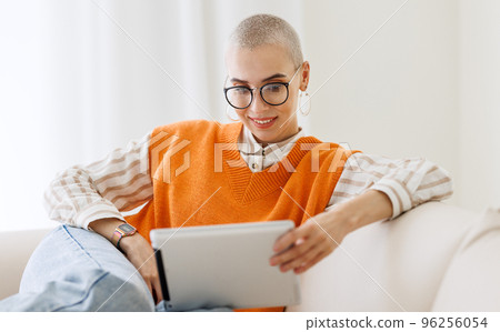 Beautiful woman freelancer with very short hair working at tablet at home Beautiful woman freelancer with very short hair working at tablet at home 96256054