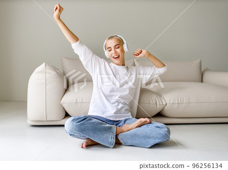 Beautiful woman meloman with very short hair listens to music and sings near couch Beautiful woman meloman with very short hair listens to music and sings near couch 96256134