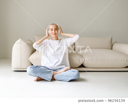 Beautiful woman meloman with very short hair listens to music near couch 96256139