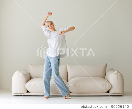 Beautiful woman meloman with very short hair dancing near couch Beautiful woman meloman with very short hair dancing near couch 96256140