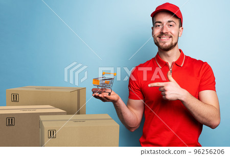 Courier has a small cart in hand. Concept of online shop. Emotional expression. Cyan background Courier has a small cart in hand. Concept of online shop. Emotional expression. Cyan background 96256206