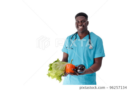 A smiling African-American doctor holds fresh vegetables in his hands on an isolated white background 96257134