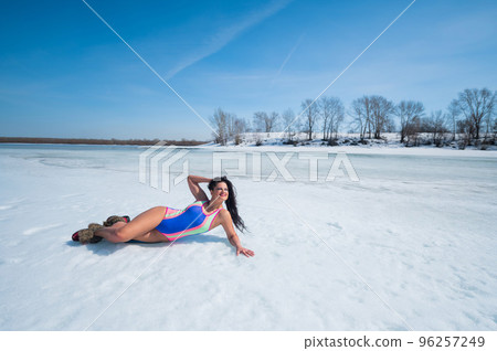 Caucasian woman in a swimsuit sunbathes on the snow in winter. 96257249