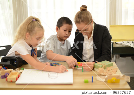 The teacher is teaching a young child to paint happily on paper. Look at the little child who is focused and poised, very focused. The teacher is teaching a young child to paint happily on paper. Look at the little child who is focused and poised, very focused. 96257637