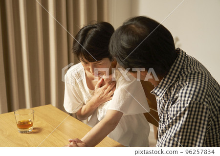 Middle-aged woman with chest pain in the living room at night Middle-aged woman with chest pain in the living room at night 96257834