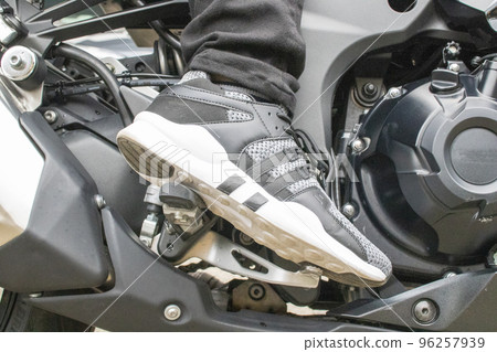 Putting one's foot on the right step of the motorcycle and stepping on the brake Putting one's foot on the right step of the motorcycle and stepping on the brake 96257939