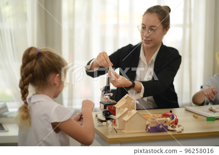 Friendly teachers help elementary school students in class. 96258016