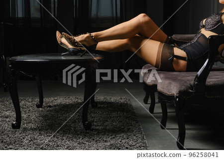 Woman in stockings is sitting on the sofa with her feet on the coffee table Woman in stockings is sitting on the sofa with her feet on the coffee table 96258041