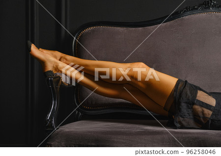 Female legs in stockings with garter belt on sofa Female legs in stockings with garter belt on sofa 96258046