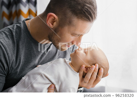 Portrait of a young Caucasian father keeping his newborn son at home. Portrait of a young Caucasian father keeping his newborn son at home. 96258320