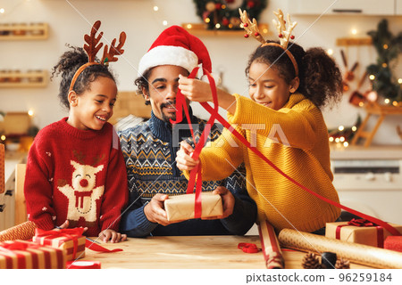 Happy ethnic family father and children pack Christmas gifts Happy ethnic family father and children pack Christmas gifts 96259184