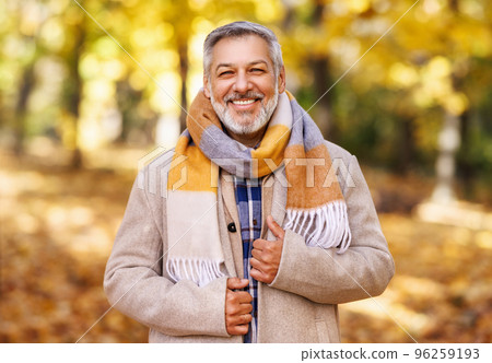 Happy positive mature man with broad smile in elegant clothes on an autumn walk in city park Happy positive mature man with broad smile in elegant clothes on an autumn walk in city park 96259193