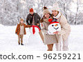 Cheerful family parents with kids in snowy winter park have fun and actively relax outdoors 96259221