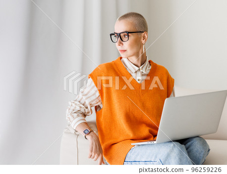 Beautiful woman freelancer in glasses with very short hair working at laptop at home Beautiful woman freelancer in glasses with very short hair working at laptop at home 96259226