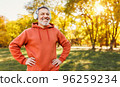 Happy positive mature man with broad in headphones smile while doing sport in city park 96259234