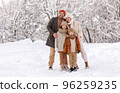 Happy family in warm clothes smiling at camera while playing on fresh air in winter snowy forest 96259235