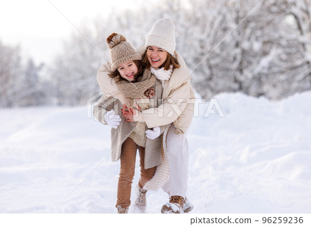 Happy mother embracing little girl daughter while having fun in snowy weather outdoor Happy mother embracing little girl daughter while having fun in snowy weather outdoor 96259236