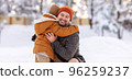 Happy family enjoying snowy weather outdoor, dad with little son hugging during walk in winter park 96259237