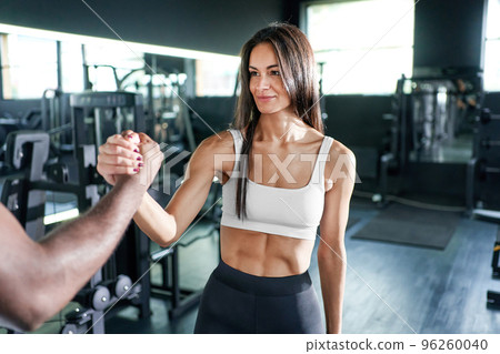 trainer and a young fitness woman shaking hands with each other. 96260040