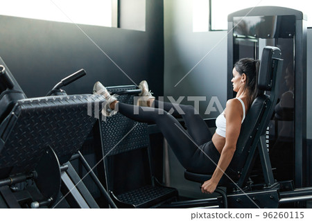 fitness woman performing exercises on a leg simulator. 96260115