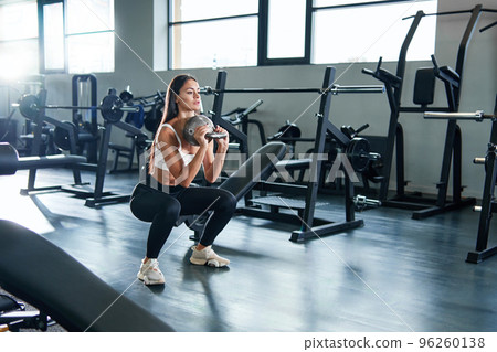 fitness woman performing squat exercises with dumbbells. 96260138