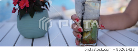 Female hand holding alcoholic cocktail with ice mojito closeup Female hand holding alcoholic cocktail with ice mojito closeup 96261428