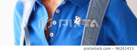 Backpack hanging on shoulders of woman in blue t-shirt closeup 96261453