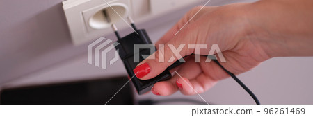 Woman hand plugging mobile phone charger into socket closeup Woman hand plugging mobile phone charger into socket closeup 96261469