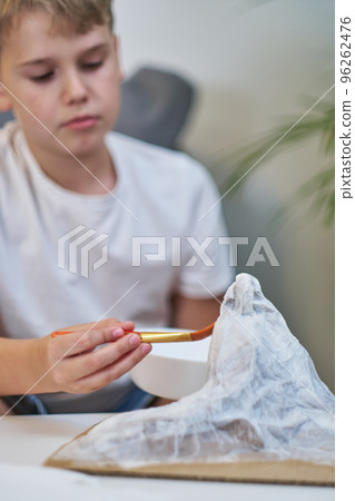 Schoolboy makes creative project in form of papier mache mountain. Schoolboy makes creative project in form of papier mache mountain. 96262476