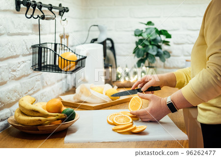 How to Dry Orange Slices for Holiday Decor. Process of Drying Orange Slices in the Oven. Woman cutting slices of orange and citrus fruits for drying in oven in home kitchen How to Dry Orange Slices for Holiday Decor. Process of Drying Orange Slices in the Oven. Woman cutting slices of orange and citrus fruits for drying in oven in home kitchen 96262477