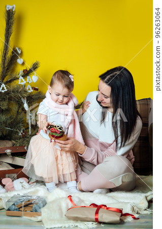 Boxing day and unpacking Christmas gift boxes. Cute Little baby toddler girl and mom unpack gift boxes near the Christmas tree at home. Merry Christmas and a Happy New Year 96263064